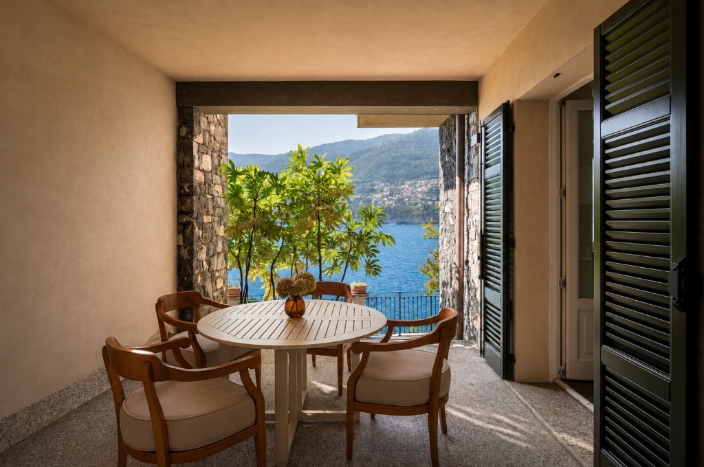 Covered terrace dining with round table, wooden chairs and direct lake and mountain views