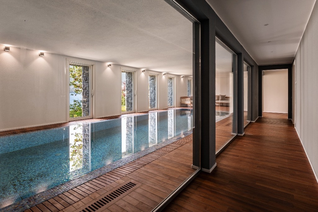 Heated indoor pool with teak decking, glass walls and lake views