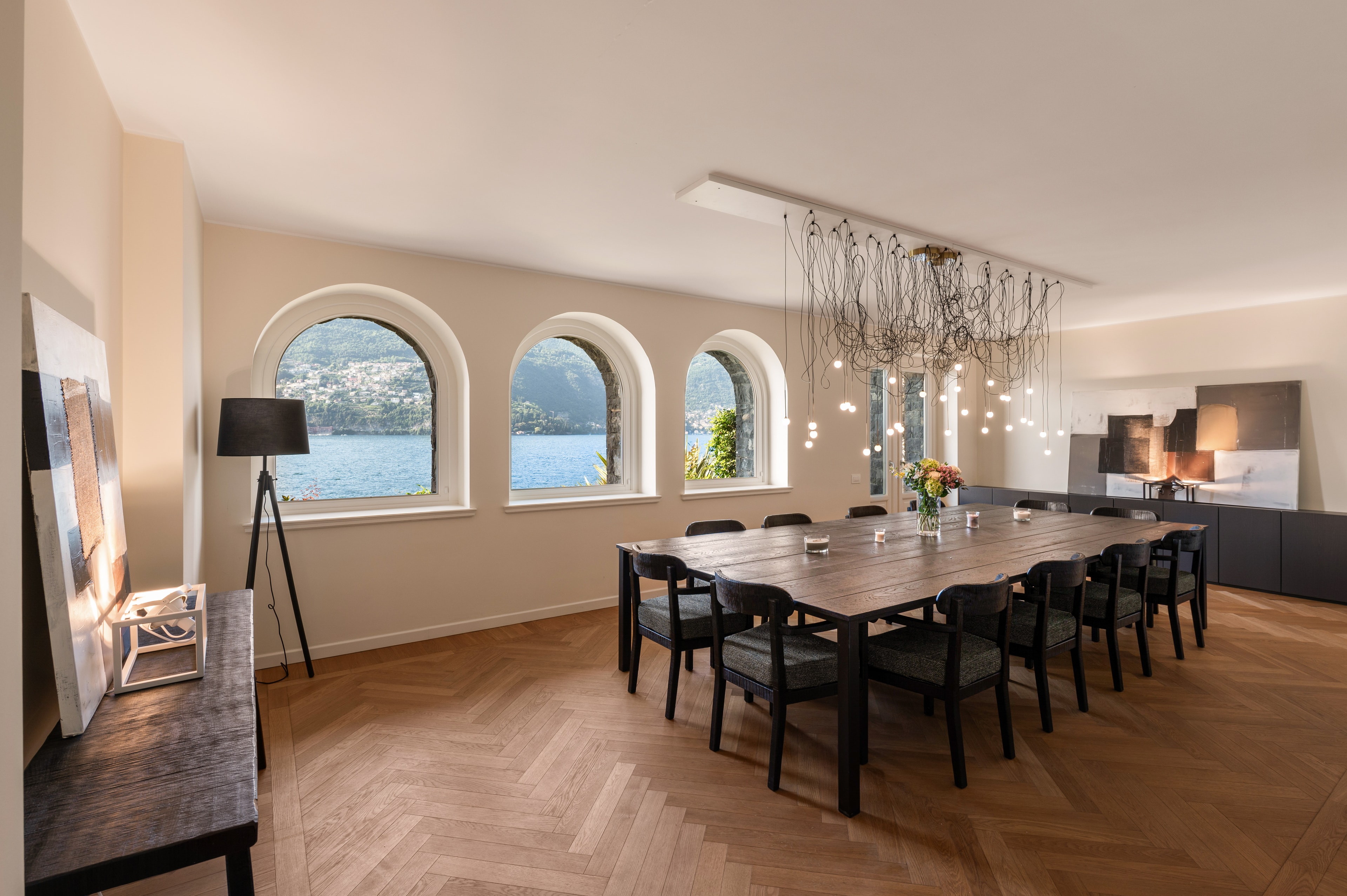 Dining room with arched lake-view windows and sculptural pendant lighting