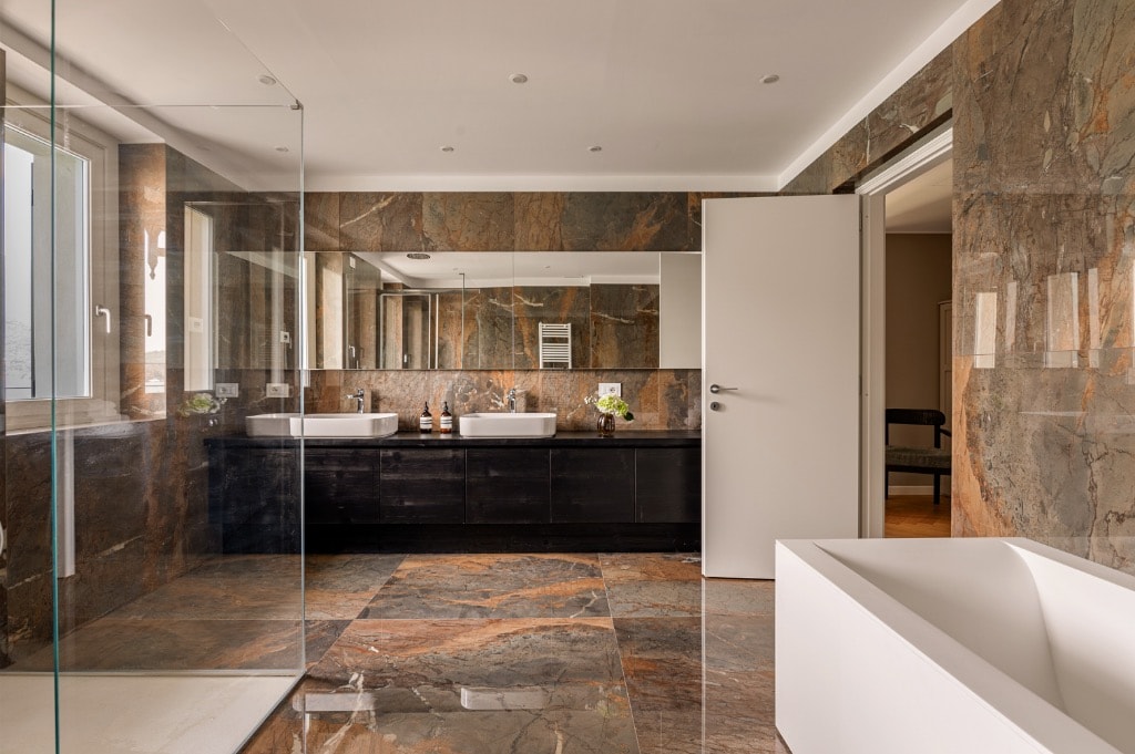 Master bathroom with full-height marble walls, freestanding bath and double vanity