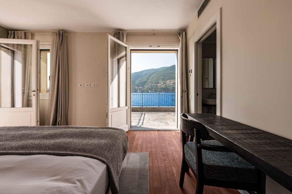 Bedroom with terrace doors opening to lake and mountain views